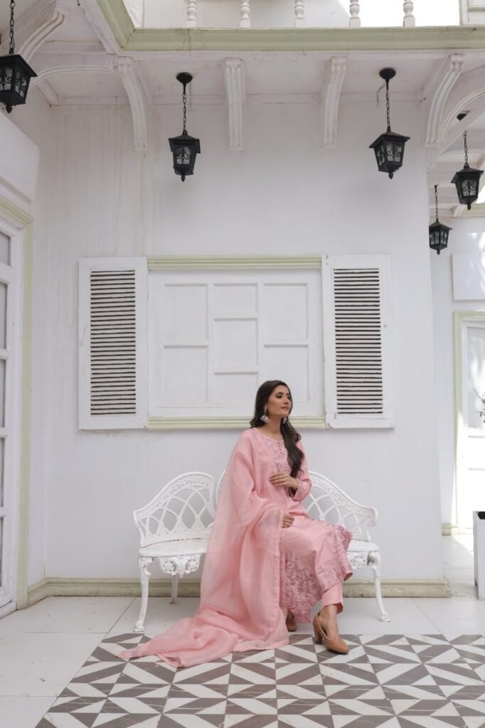 Woman wearing a light pink embroidered kurta with matching dupatta and floral detailing