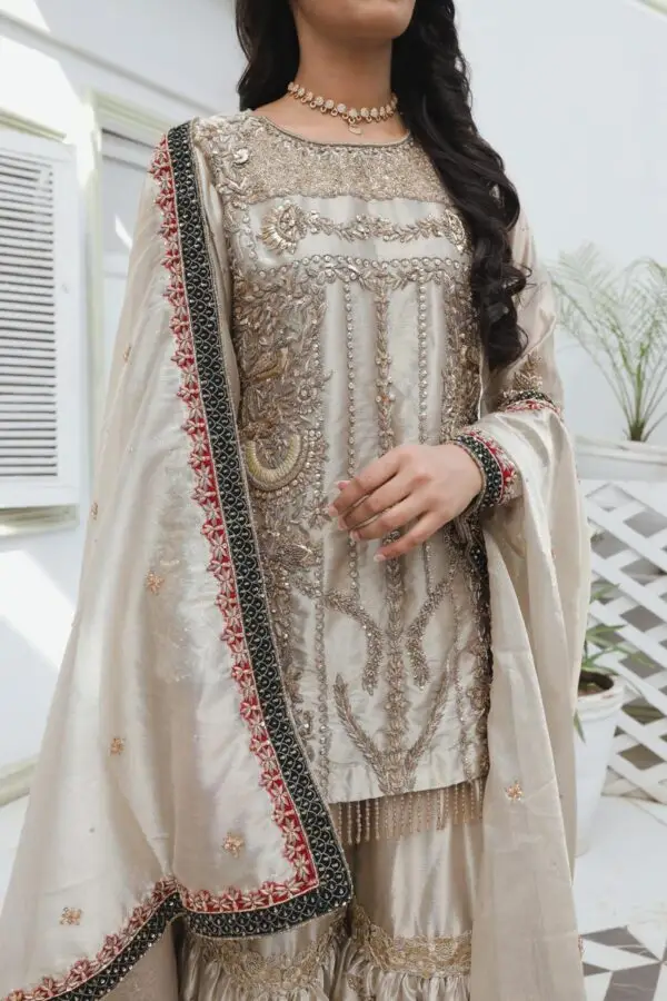 Champagne-gold bridal dress in silk tissue with fully hand-embroidered shirt and garara, handmade sleeve hangings, and zari tissue dupatta with velvet embroidered borders.